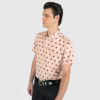 Short sleeve button up pink shirt with black polka dots.