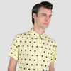 Short sleeve button up light yellow shirt with black polka dots.