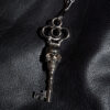 A silver-plated skeleton key necklace that hangs from a long, 18 inch stainless steel chain. The chain length can be adjusted for a shorter chain.