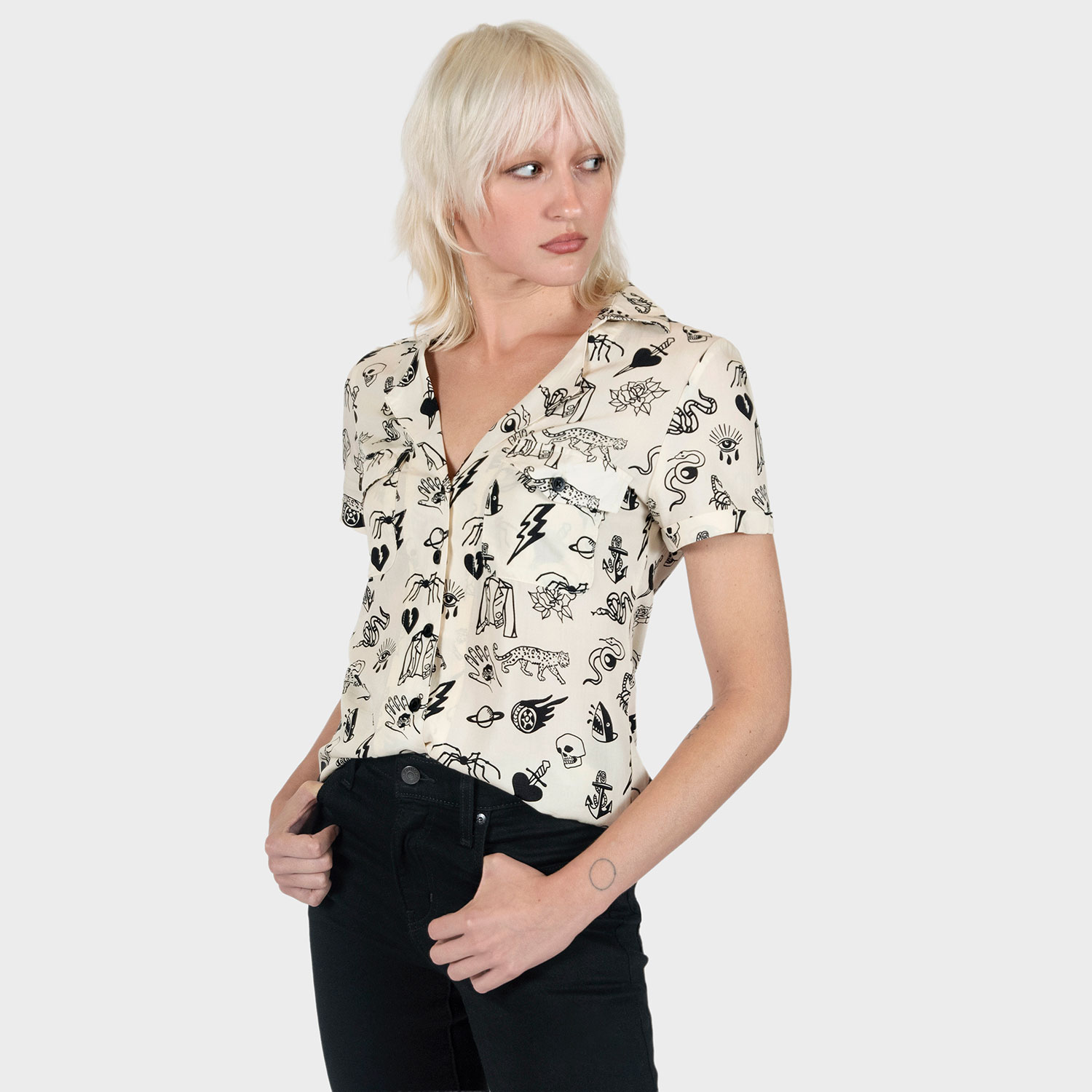 The Good Bad Not Evil shirt, filled with our doodle art. There are too many doodles to mention, but our favorites are snakes, dagger and hearts, roses, spiders, teardrop eyes, lightning bolts, cheetahs, and more. Soft cream fabric, a deep-V button up closure, dual chest pockets, and cuffed short sleeves.