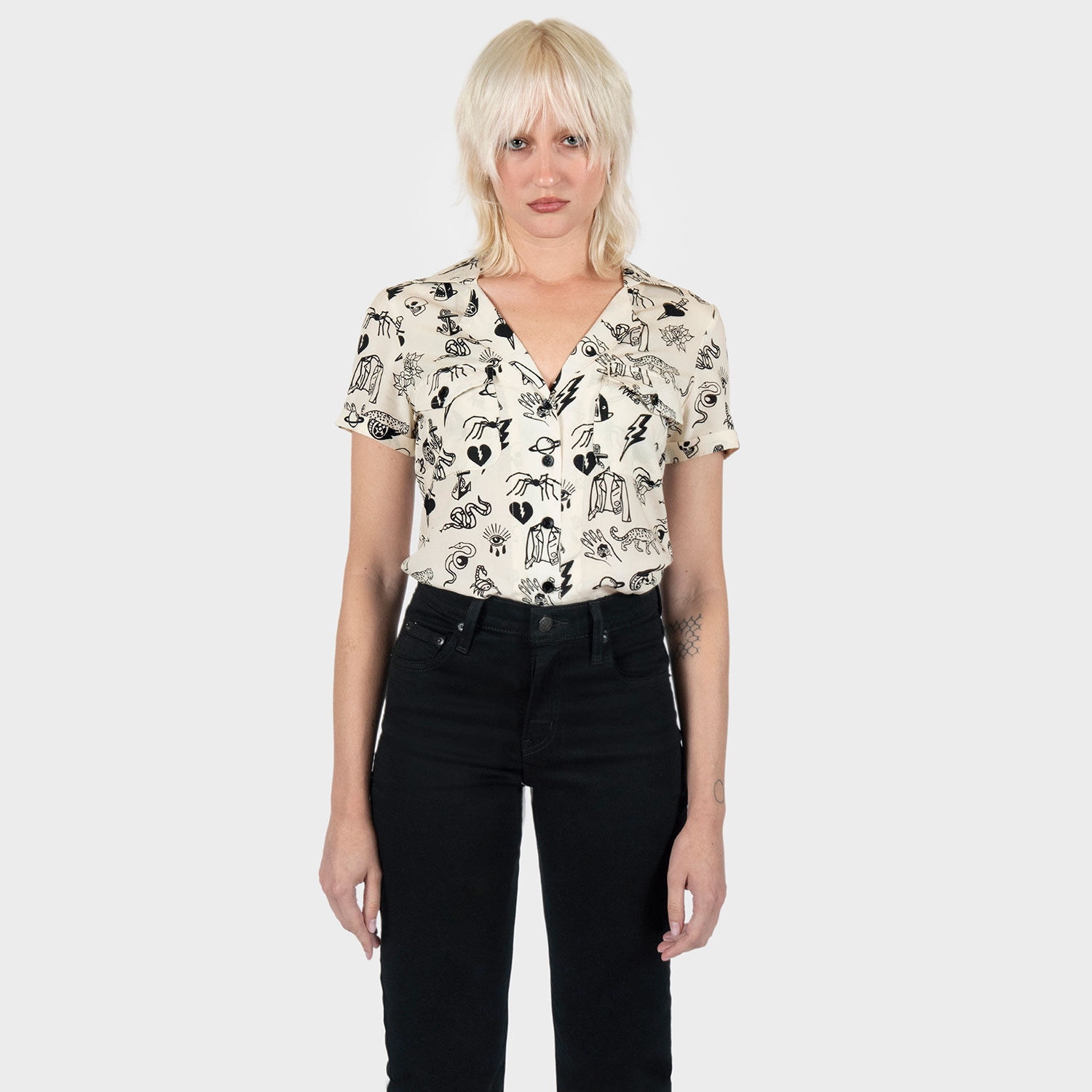 The Good Bad Not Evil shirt, filled with our doodle art. There are too many doodles to mention, but our favorites are snakes, dagger and hearts, roses, spiders, teardrop eyes, lightning bolts, cheetahs, and more. Soft cream fabric, a deep-V button up closure, dual chest pockets, and cuffed short sleeves.