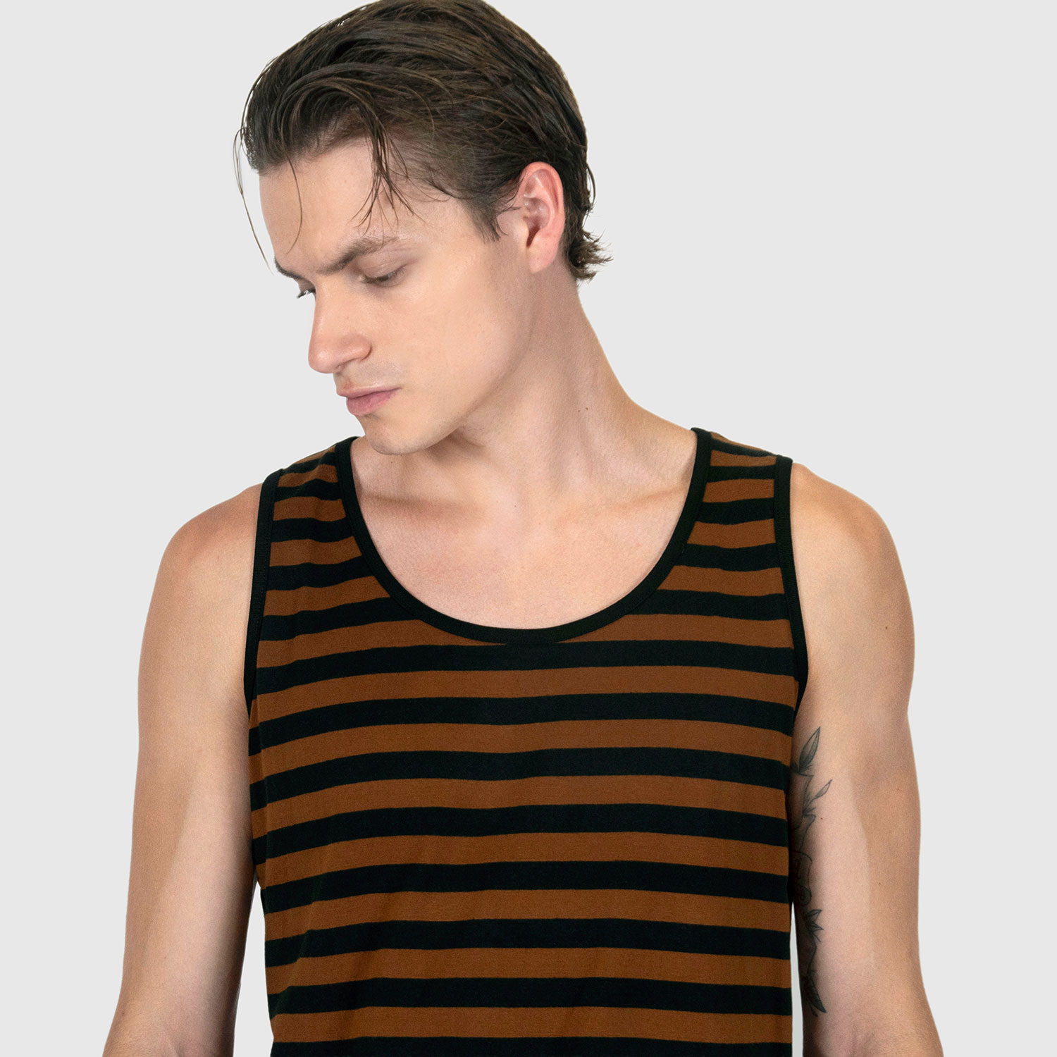 The Richie is a black and brown, short sleeve striped tank top. This soft cotton-poly blend allows the fabric to drape comfortably on your torso. It features a subtle diamond embroidered on the lower corner. This is our Bucktown fit.