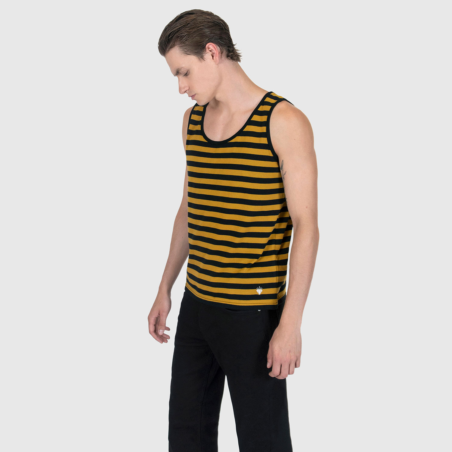 The Richie is a black and yellow striped tank top. This soft cotton-poly blend allows the fabric to drape comfortably on your torso. It features a subtle diamond embroidered on the lower corner.