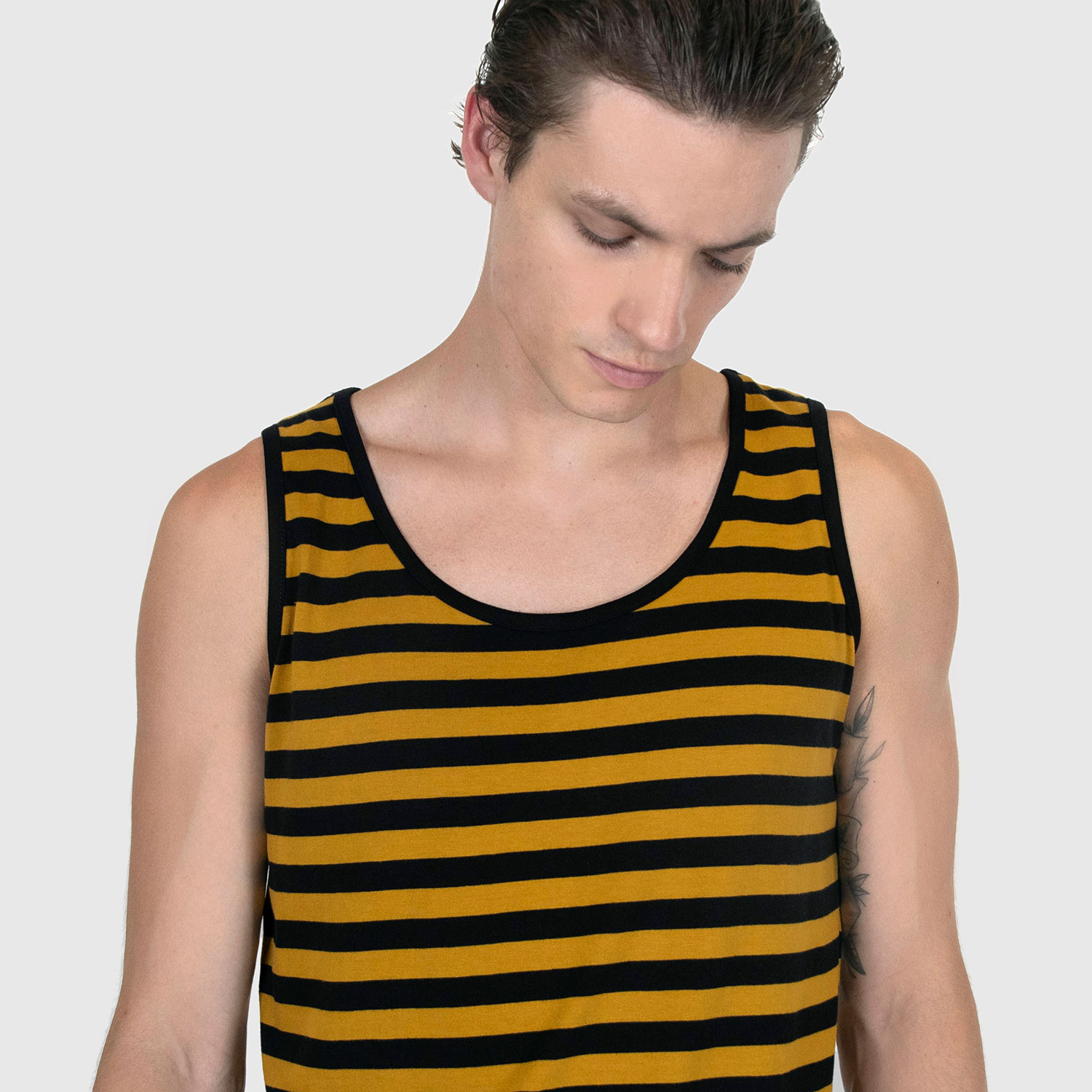 The Richie is a black and yellow striped tank top. This soft cotton-poly blend allows the fabric to drape comfortably on your torso. It features a subtle diamond embroidered on the lower corner.