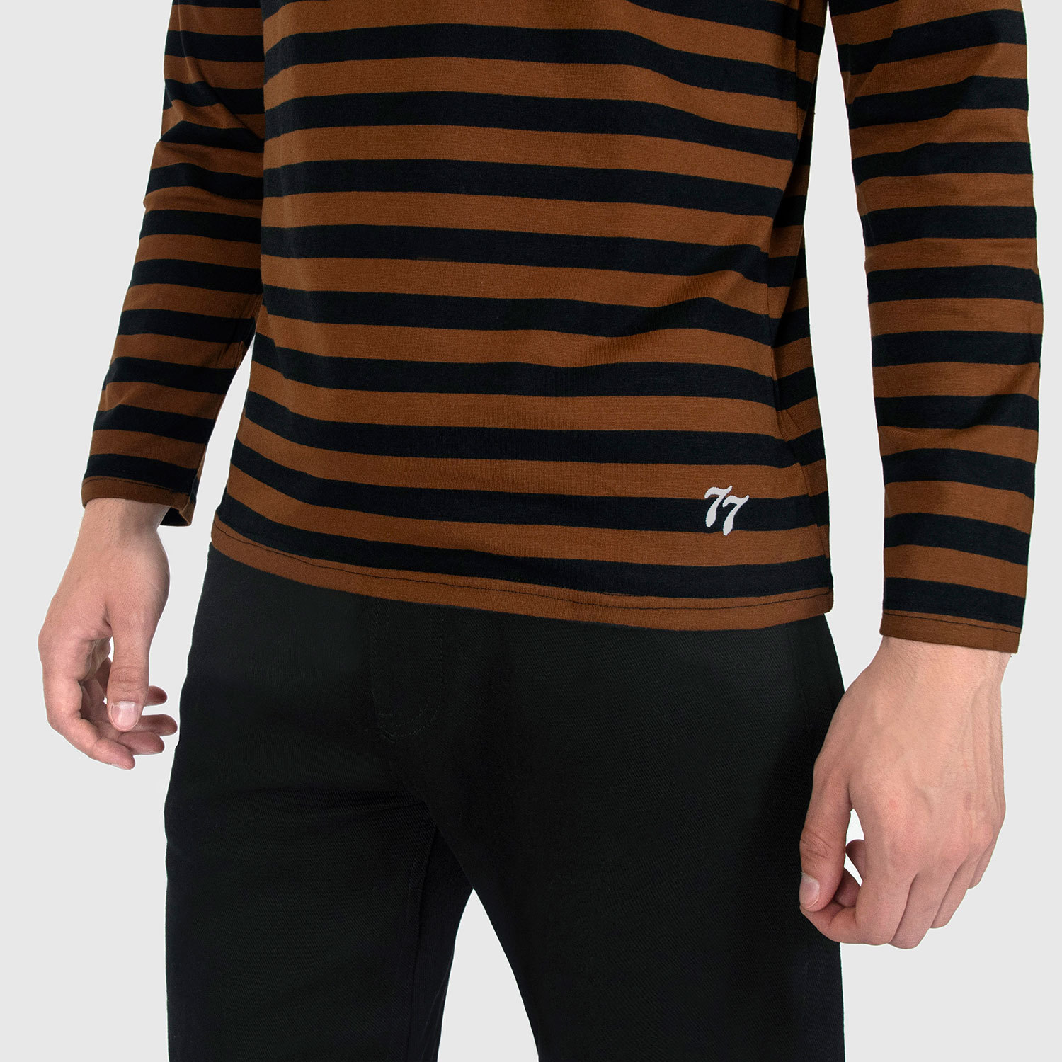 The Fitz 77 is a black and brown striped, long sleeve t-shirt. This soft cotton-poly blend allows the fabric to drape comfortably on your torso. It features a subtle 77 embroidered on the lower corner. This is our Bucktown fit.