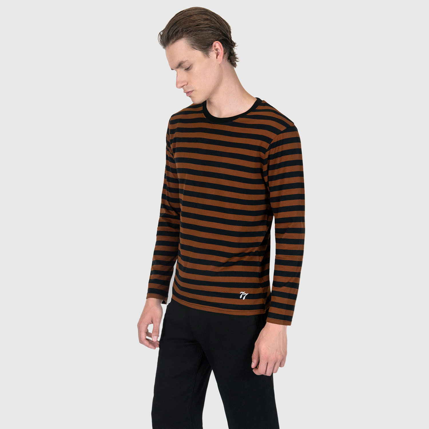 The Fitz 77 is a black and brown striped, long sleeve t-shirt. This soft cotton-poly blend allows the fabric to drape comfortably on your torso. It features a subtle 77 embroidered on the lower corner. This is our Bucktown fit.